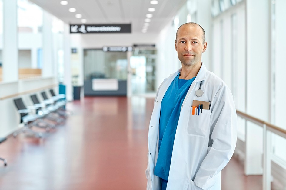 Male doctor in hospital corridor with a stethoscope and a notebook and pens in his side pocket