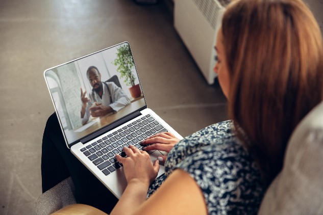 Woman sitting in front of laptop watching a video of a male doctor speak to camera